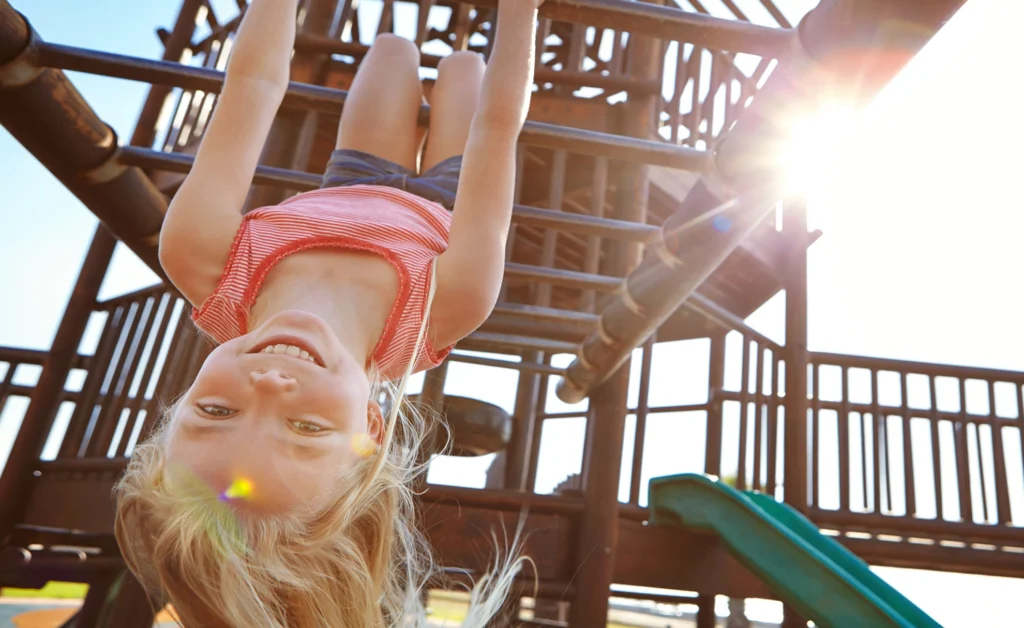 girl hanging upside down on a playground