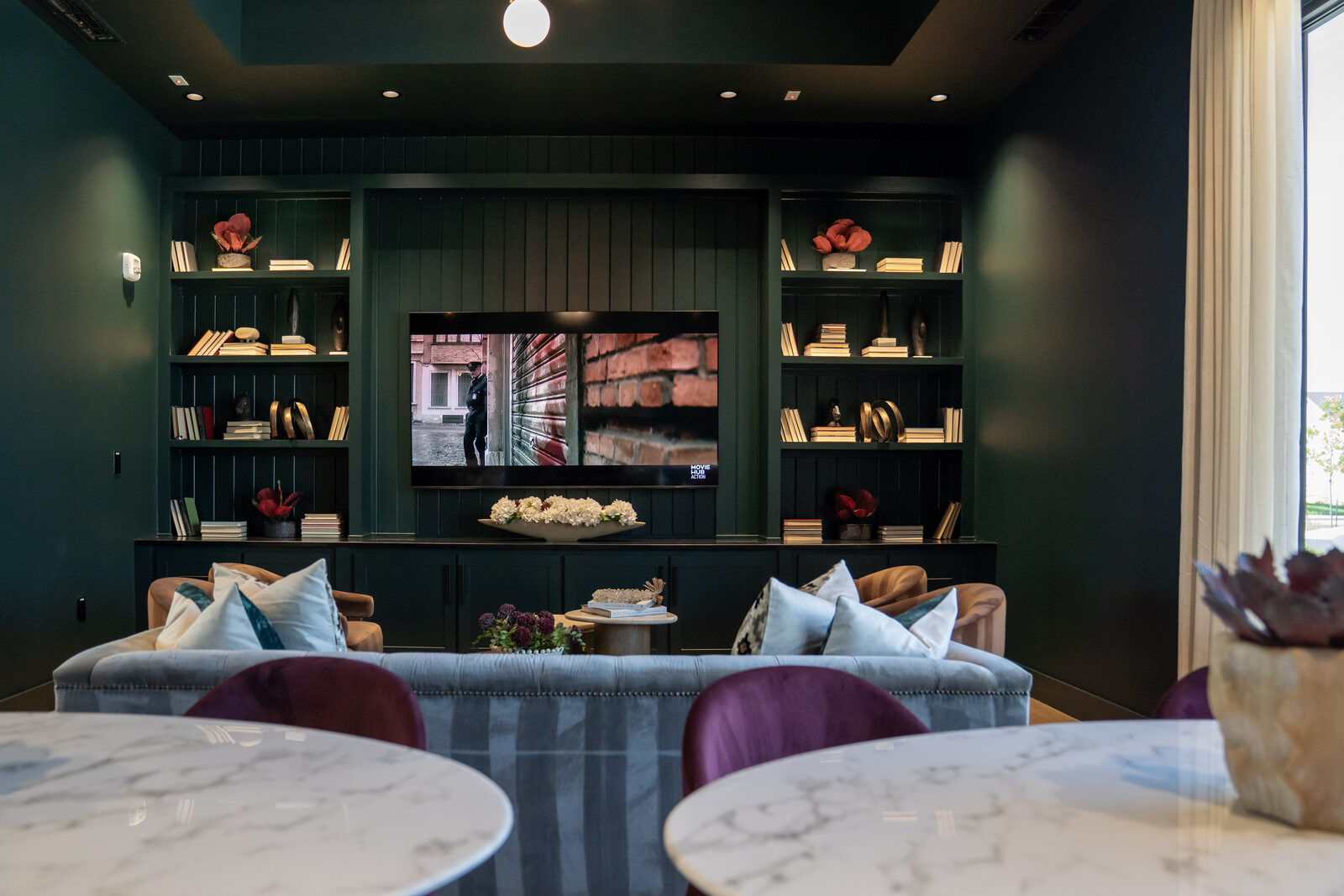 The Lakehouse media lounge, with a large screen set into deep green built-ins and lounge seating.